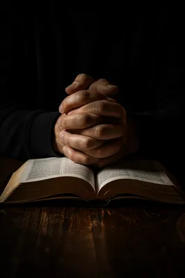 Praying Hands Over Open Bible