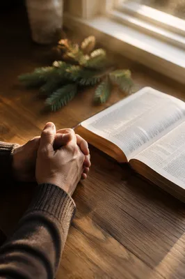 Praying Hands Beside Open Bible