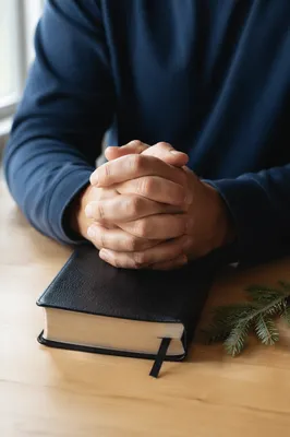 Praying Hands Resting on Leather Bible