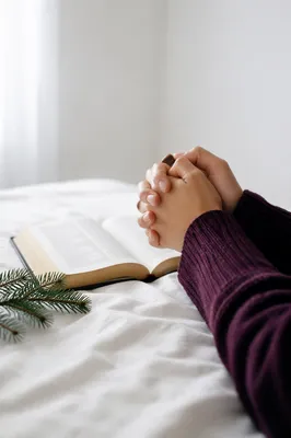 Praying Hands Beside Open Bible