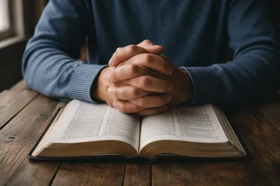 Praying Hands Resting on Open Bible
