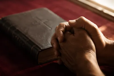 Praying Hands Beside Leather Bible