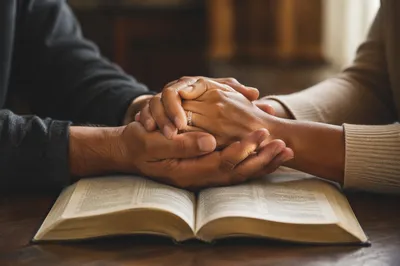 Praying Hands Over Open Bible