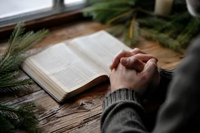 Praying Hands Beside Open Bible