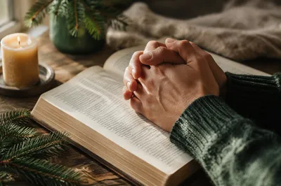 Praying Hands on Bible with Evergreen Sprigs