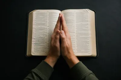 Praying Hands Over an Open Bible