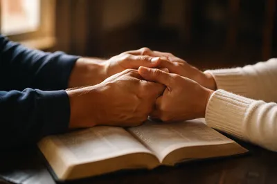 Praying Hands Over Open Bible