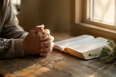 Praying Hands Beside Open Bible