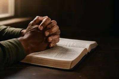 Praying Hands Resting on Open Bible