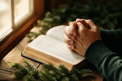 Praying Hands Over Bible with Evergreen