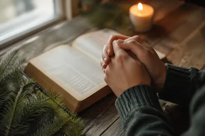Praying Hands Beside Open Bible