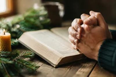 Praying Hands Beside Open Bible