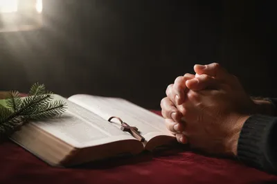 Praying Hands Beside Open Bible