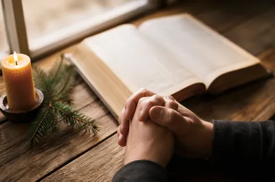 Praying Hands Beside Open Bible