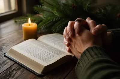 Praying Hands Beside Open Bible