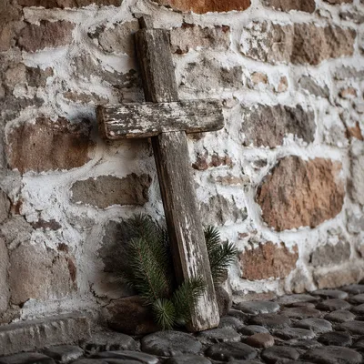 Weathered Wooden Cross Against Stone Wall