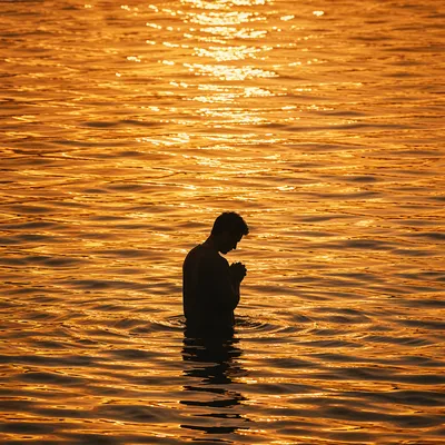 Silhouetted Prayer in Golden Sunset Water