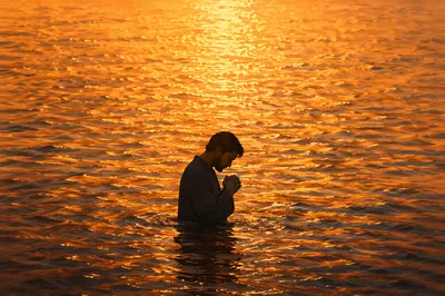 Silhouetted Prayer in Golden Sunset Water