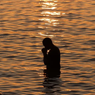Silhouetted Prayer in Golden Sunset Waters