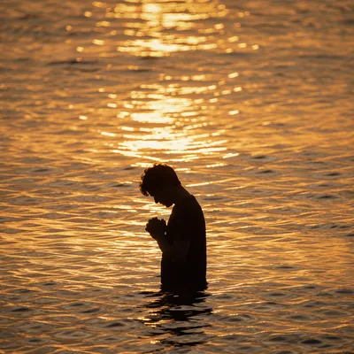 Silhouetted Prayer in Golden Sunset Water