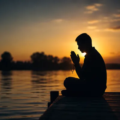 Silhouette Praying at Sunset by Water