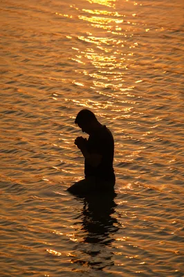 Silhouetted Prayer in Golden Sunset Waters