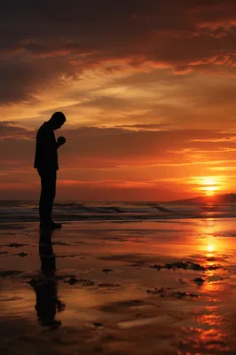 Silhouetted Prayer on Sunset Shoreline