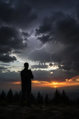 Silhouette Praying Beneath Stormy Sunset Sky