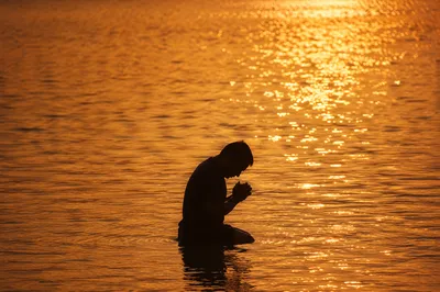 Silhouetted Prayer in Golden Sunset Waters