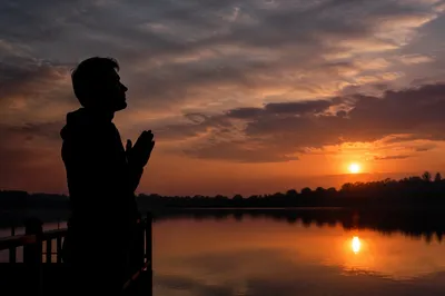 Praying Silhouette by Lakeside Sunset