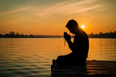 Silhouette Praying on Dock at Sunset