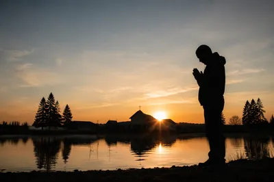Silhouetted Prayer by Sunset Lakeshore
