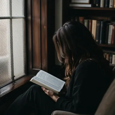 Woman Reading Bible Beside Frosted Window