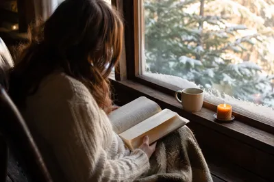 Woman Reading Bible Beside Winter Window