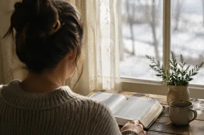 Woman Reading Bible by Winter Window
