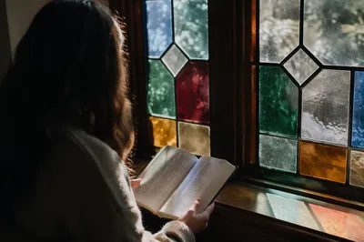 Woman Reading Bible by Evergreen Window