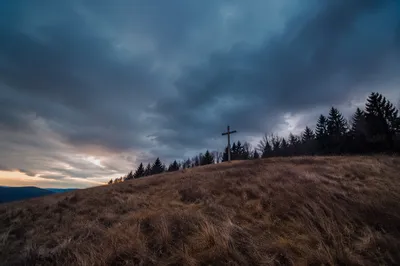 Wooden Cross on Hilltop Beneath Stormy Sky