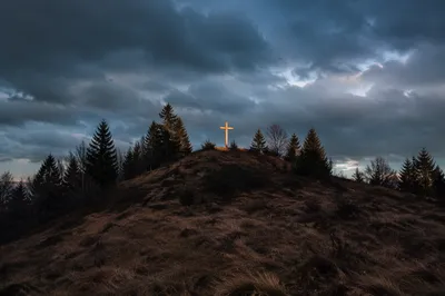 Wooden Cross on Hilltop Under Stormy Sky