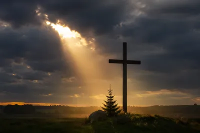 Wooden Cross Silhouette at Stormy Sunrise