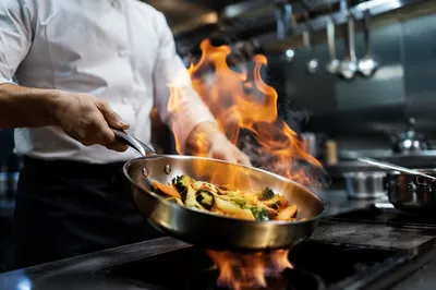 Chef Tossing Vegetables Over Kitchen Flame