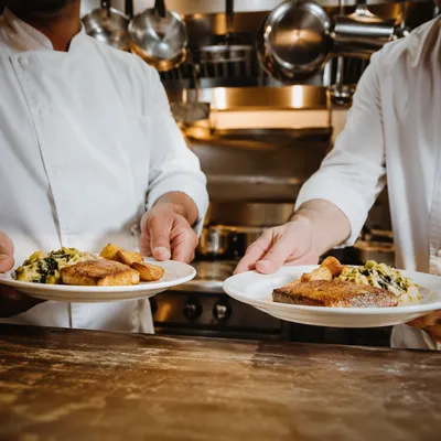 Cooks Serving Fresh Plates in Warm Kitchen