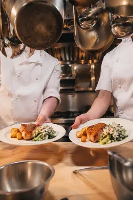 Cooks Serving Prepared Vegetables in Kitchen