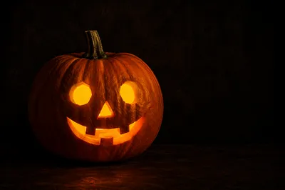 Glowing Carved Halloween Pumpkin on Dark Table