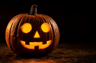 Glowing Carved Halloween Pumpkin on Dark Table