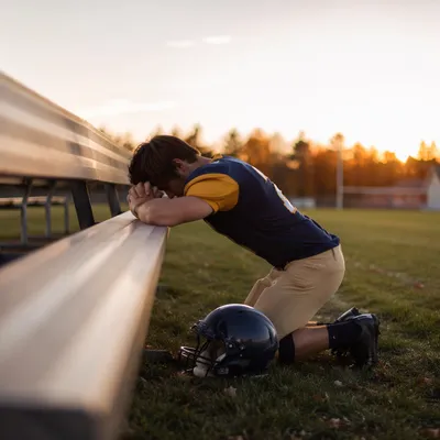 Athlete Praying on Field at Sunrise