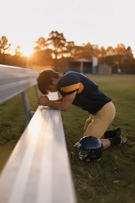 Kneeling Athlete Praying on Sunrise Field