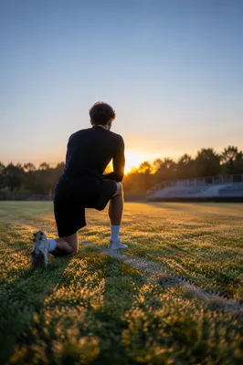 Athlete Kneeling on Field at Sunrise