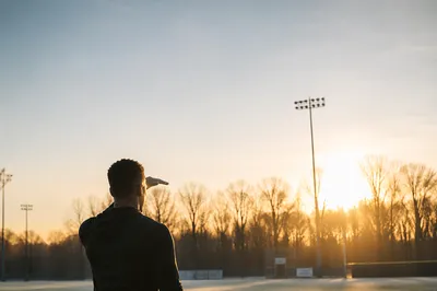 Athlete Kneeling at Sunrise on Field