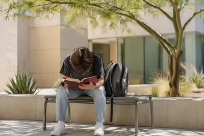 Student Reading Bible in Campus Courtyard