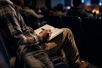 Student Reading Bible in Campus Lecture Hall
